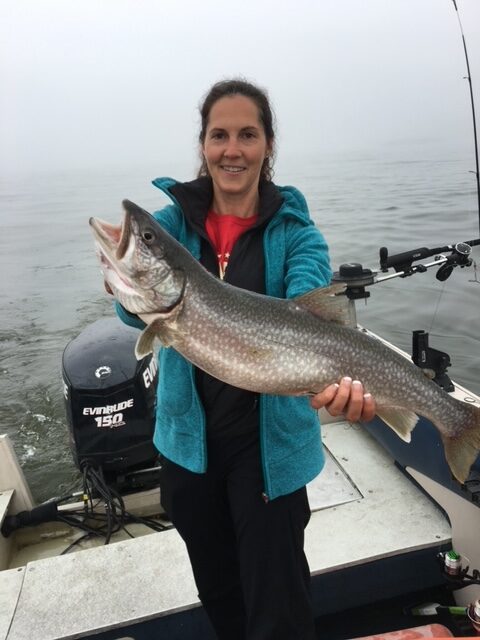 Happy Father's Day Penny Tremblay in a boat on the water holding a large fish she caught