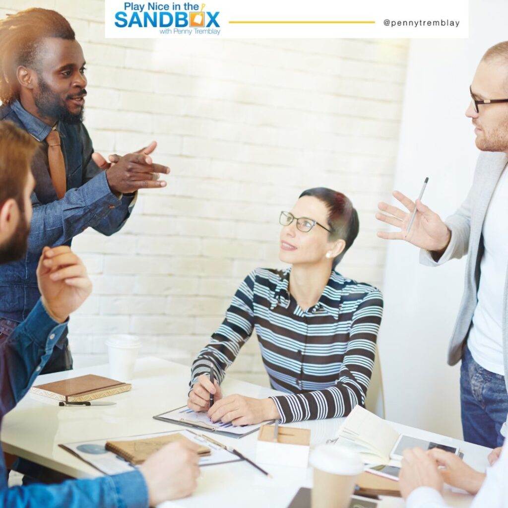 image of 2 men standing and a woman sitting at a table having a friendly debate