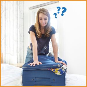 A photo of a young woman pushing down on the top of an overstuffed suitcase