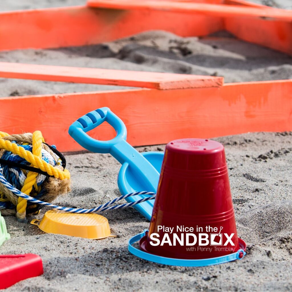 image of a sandbox with toys sitting on the outside on the ground